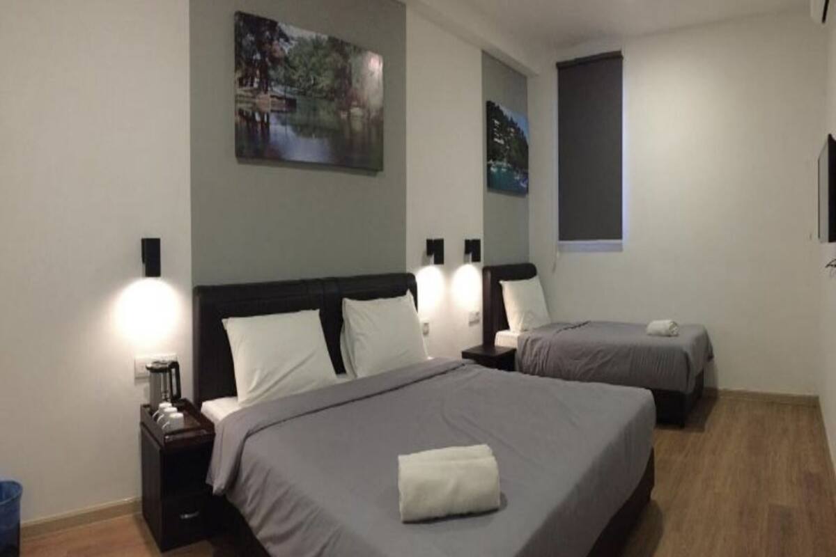 A hotel room with two beds, a nightstand, a lamp, and a painting on the wall.
