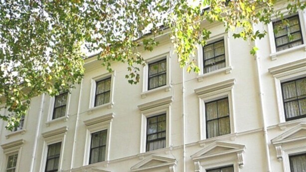 A white building with a sign reading "Ashley Hotel." It features a symmetrical facade with evenly spaced windows and a central entrance.