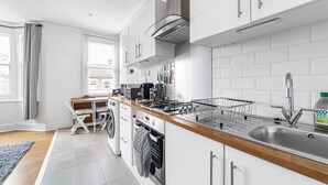 A modern kitchen with white cabinetry, a stainless steel sink, and a built-in oven.