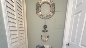 A hallway with a welcome sign, an anchor decoration, and a basket of towels.