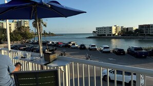 A balcony with a view of a marina, parked cars, and buildings along the waterfront.