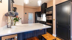 A modern kitchen with dark cabinetry, a marble countertop, and stainless steel appliances. - Paradise Row Townhouse (London)