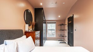 A bedroom with a bed, dresser, and a mirror. There is a window with a view of the outside. - Paradise Row Townhouse (London)