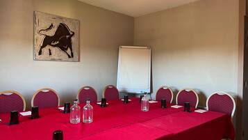 A conference room with a red table, chairs, a whiteboard, and a painting on the wall.