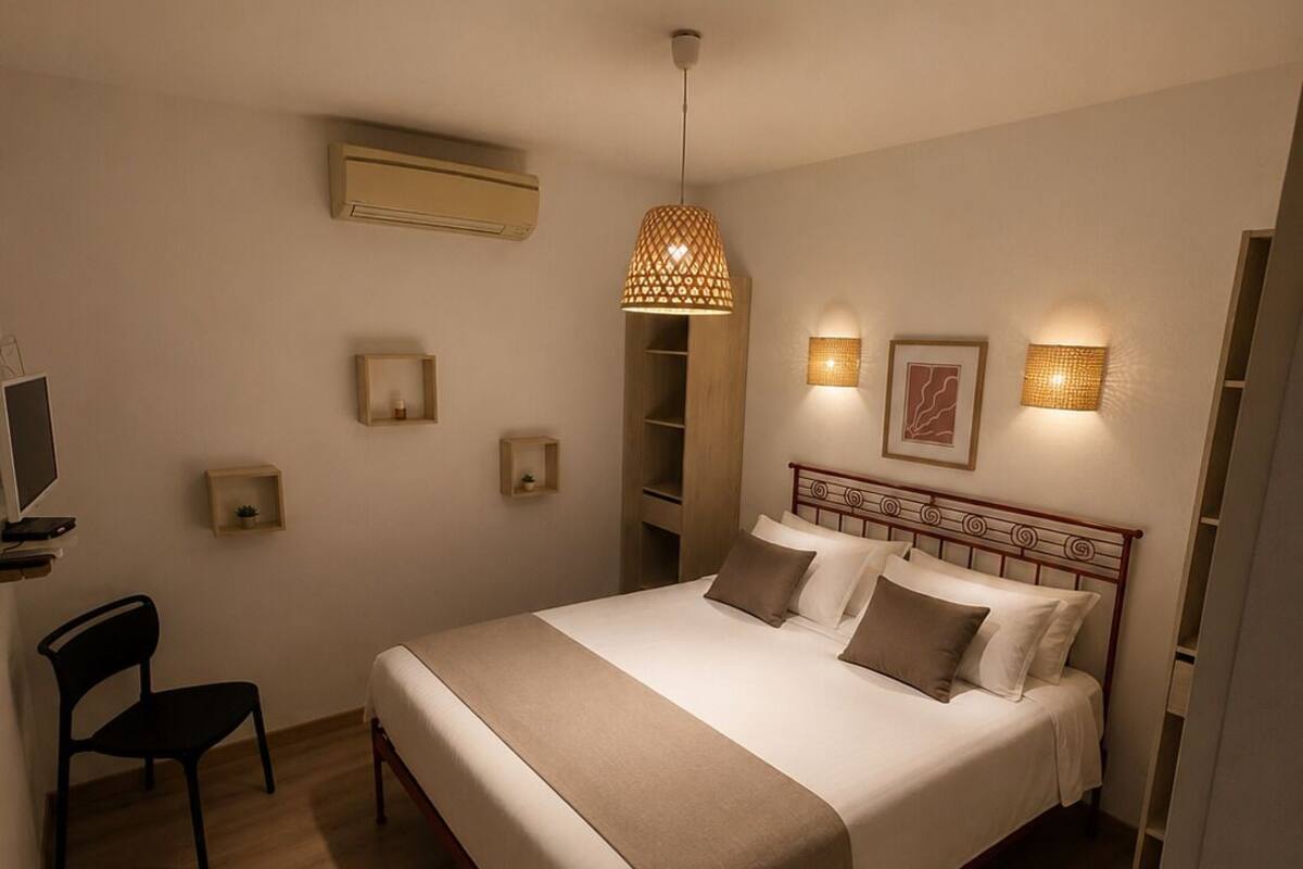 A bedroom with a bed, bedside tables, a chair, a hanging light fixture, and wall-mounted lights.