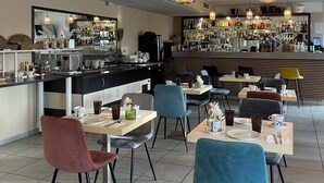 A modern cafe with a bar area, seating with tables and chairs, and a variety of beverages on display. - Hôtel Restaurant Les Jasses de Camargue (Gallargues-le-Montueux)