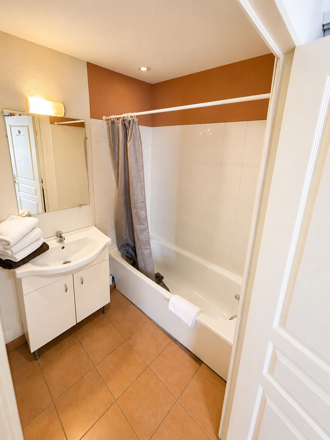 A bathroom with a sink, mirror, and bathtub.
