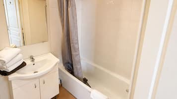 A bathroom with a sink, mirror, and bathtub.