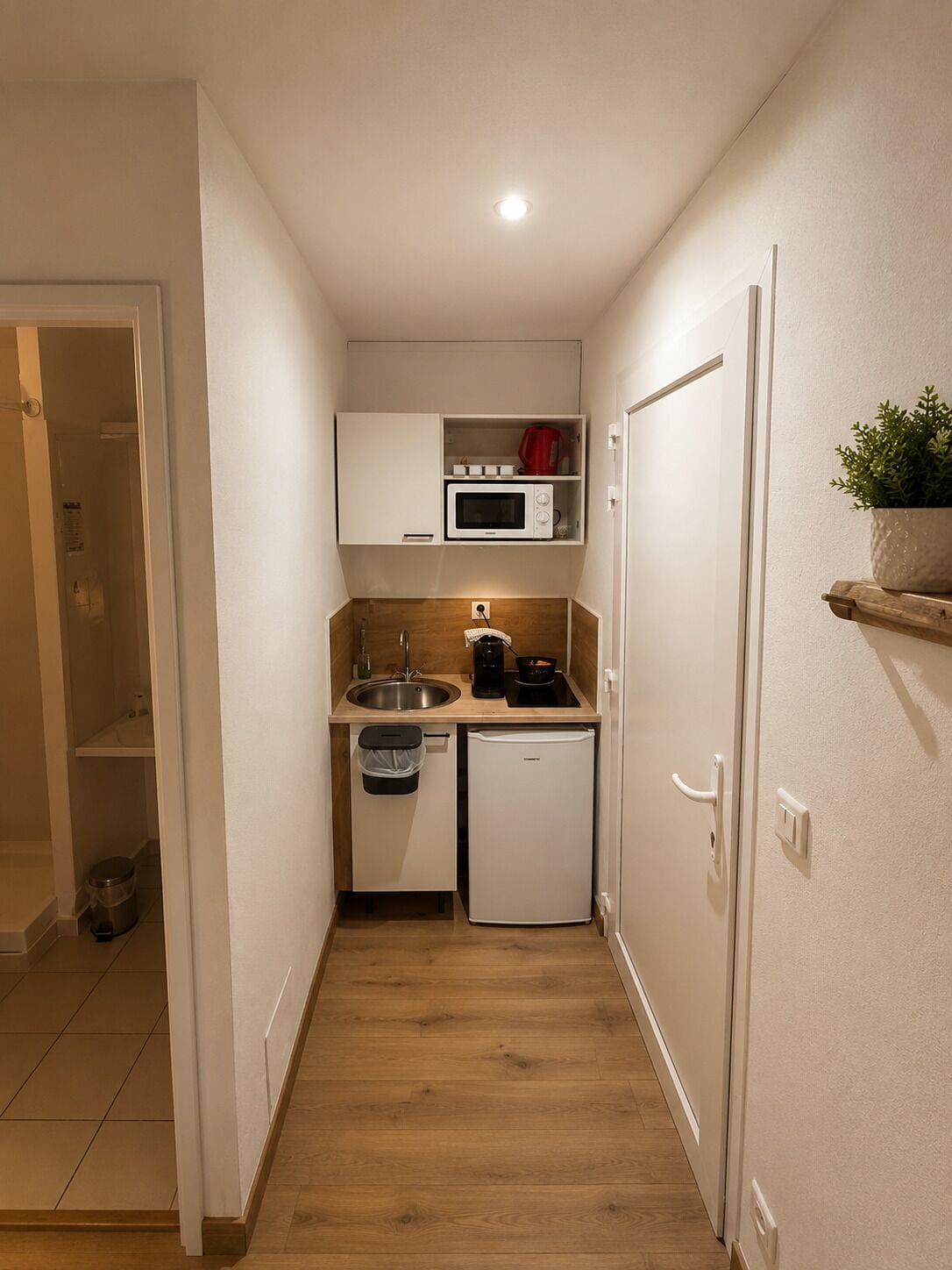 Una cocina compacta con microondas, pileta y refrigerador pequeño.