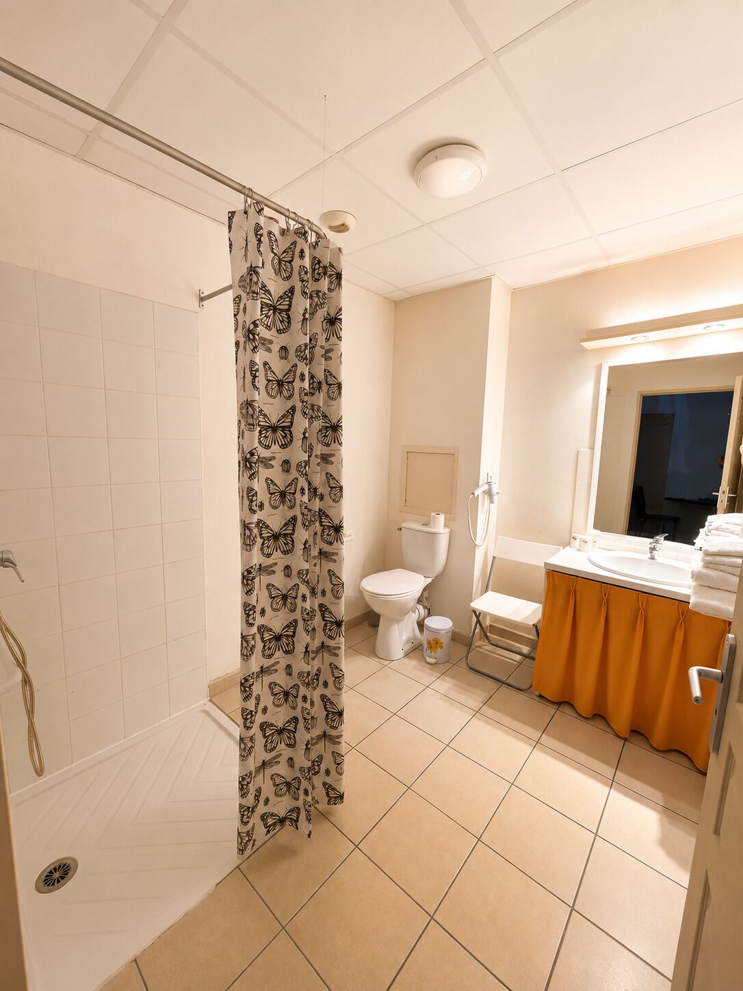 Et badeværelse med badeforhæng, toilet, vask og et vindue.