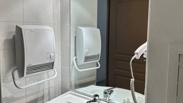 A modern bathroom with a white sink, two hand dryers, and a mirror.