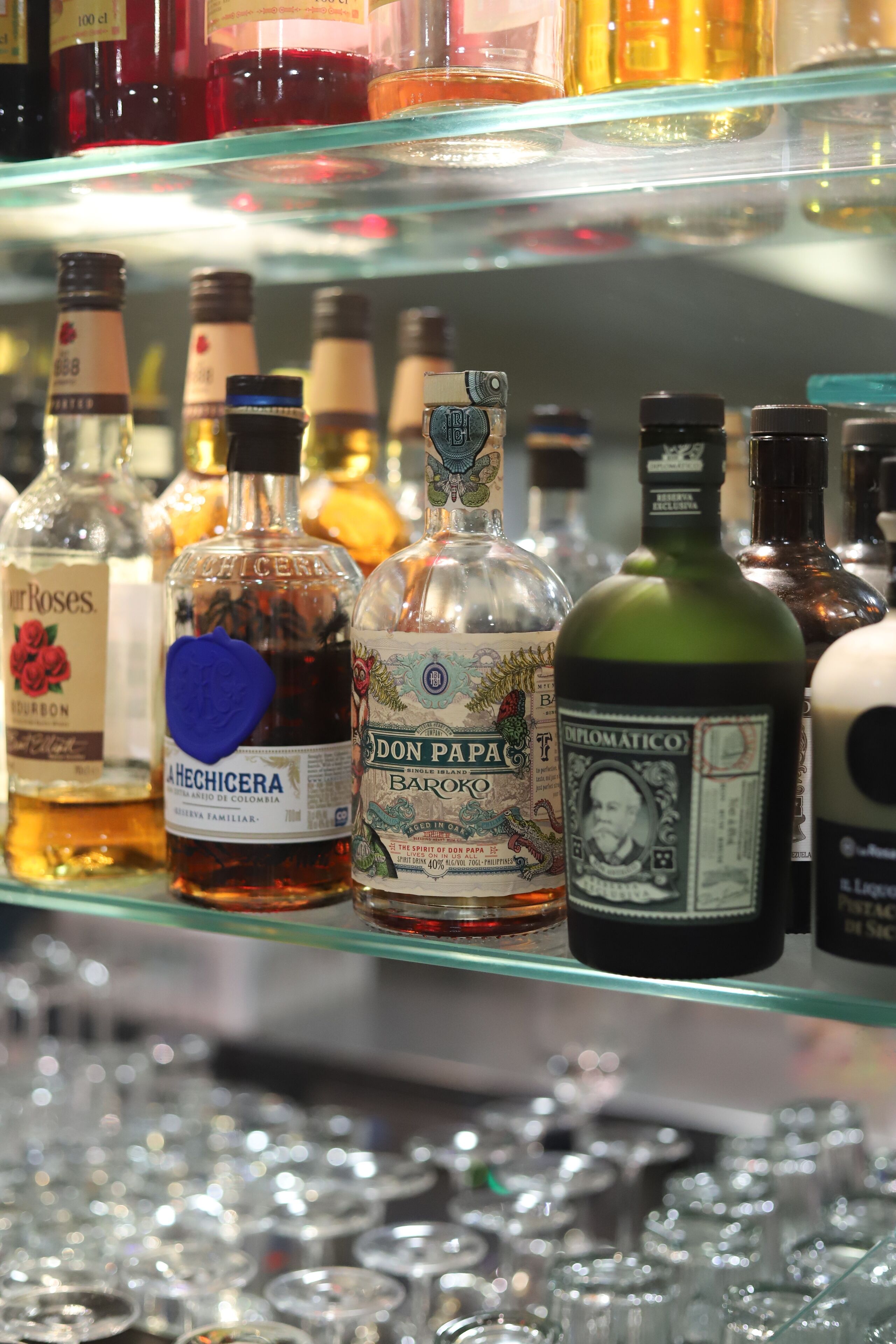 Una estantería con diversas botellas de licor, incluyendo Don Papa Baroque y Diplomatico.