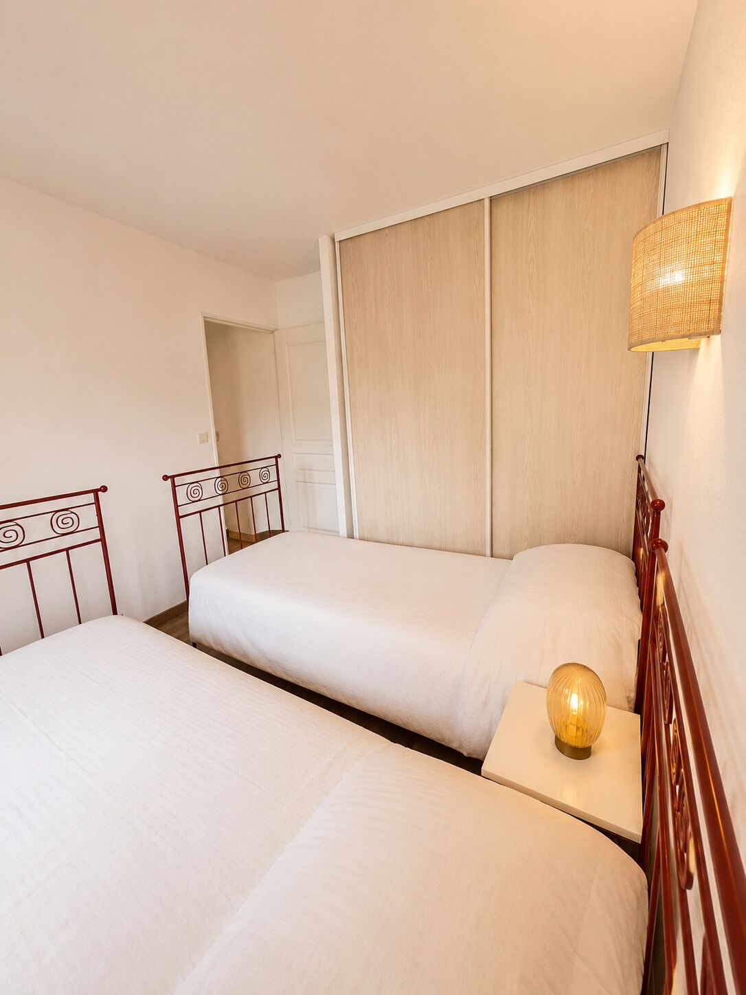 Una camera d'albergo con due letti, una lampada da comodino e un pannello di legno a caposeria.