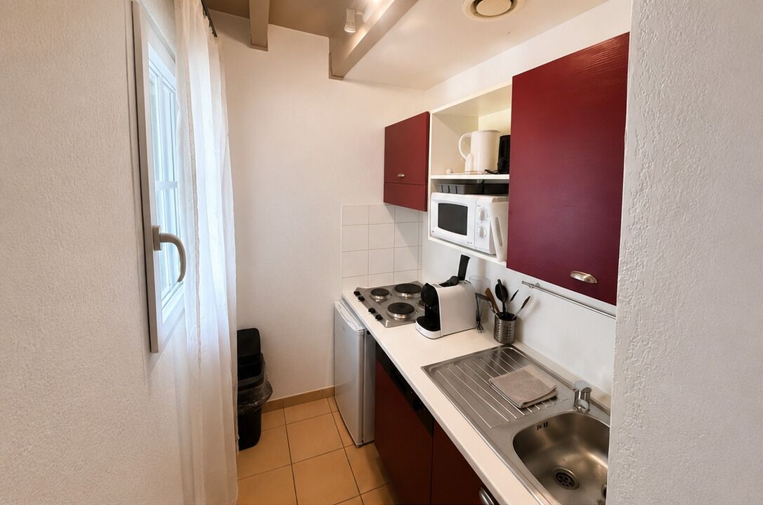 Een praktische keuken met een magnetron, fornuis, spoelbak en een kleine koelkast.