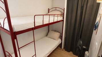Une chambre avec un lit superposé, un ventilateur de plafond et une porte avec un rideau.