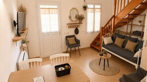 A dining area with a table, chairs, a TV, and a sofa. - Hôtel Restaurant Les Jasses de Camargue (Gallargues-le-Montueux)