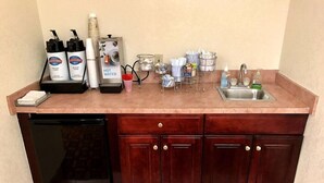 A kitchen with a dishwasher, a coffee machine, a water dispenser, and various kitchen utensils. - Seasons Inn Suites Highland (Highland)