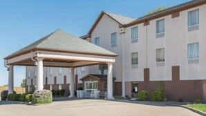 A multi-story hotel with a covered entrance and a parking area. - Seasons Inn Suites Highland (Highland)
