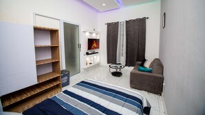 Une chambre moderne avec un lit, un canapé, une télévision et une armoire.