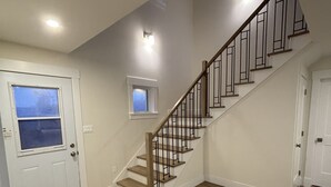 A staircase with wooden steps and metal railings, leading to a landing with a small window. - Ocean view cottages with direct beach access (Savage Harbor)
