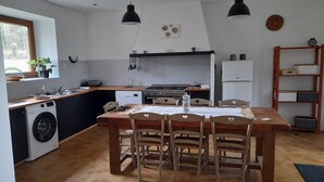 Une cuisine compacte comprenant un coin repas, un lave-linge et une table en bois avec des chaises.