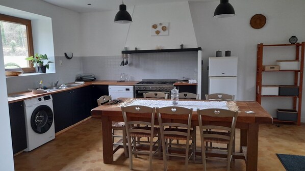 Una cocina compacta con comedor, lavadora y mesa de madera con sillas.