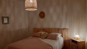 Une chambre à coucher avec une tête de lit en bois, un lit agrémenté de plusieurs oreillers, un luminaire suspendu et une table de chevet avec une lampe.
