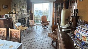 Une pièce avec une cheminée en pierre, une table à manger avec des chaises, un canapé et une grande fenêtre donnant sur un beau paysage.