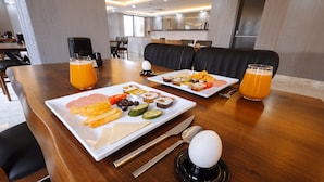 A breakfast setting with a wooden table, plates of food, and orange juice glasses. - Meyzi Hotel (Arnavutköy)