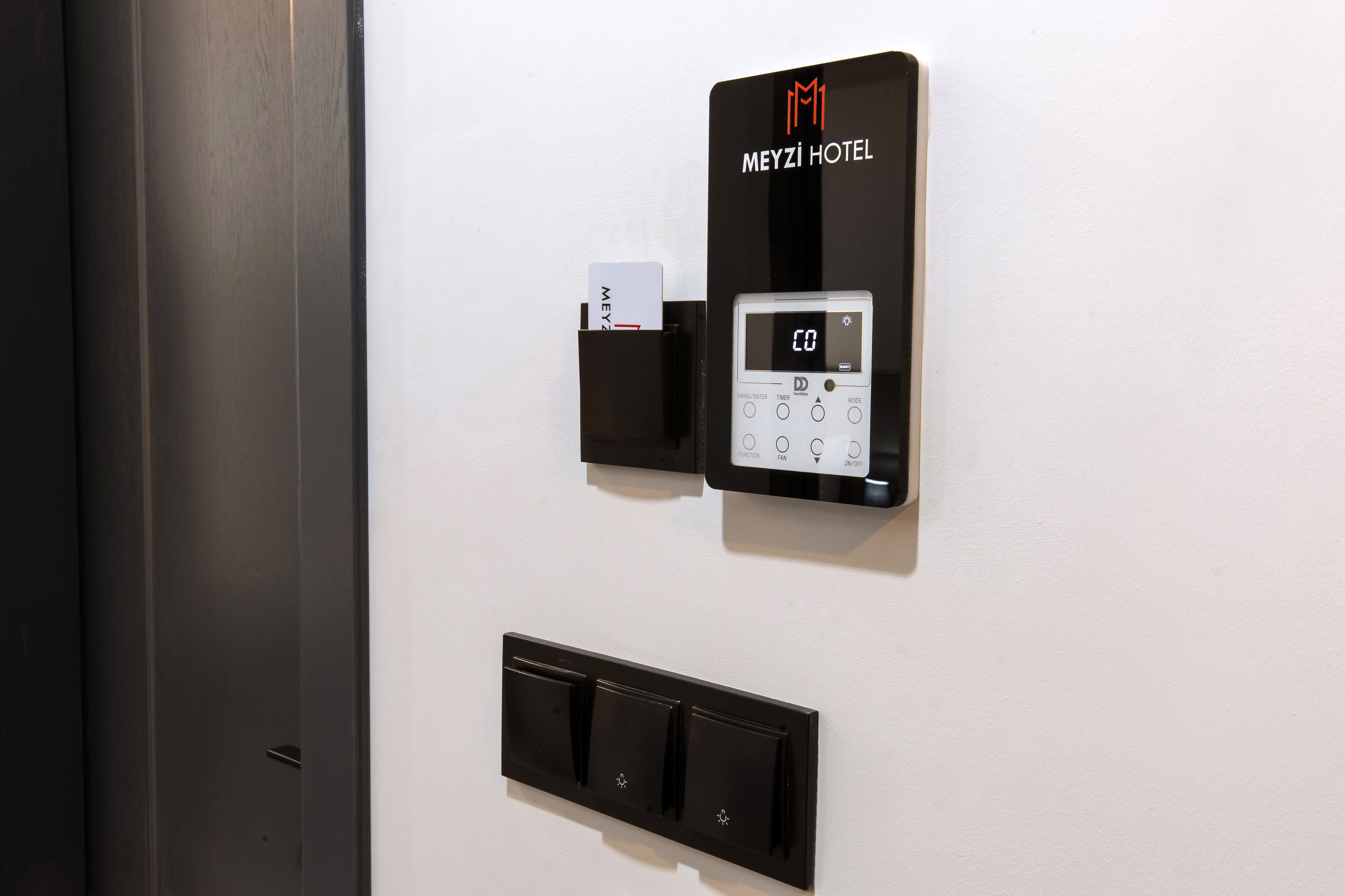Un appareil électronique fixé au mur, doté d’un clavier et d’un lecteur de cartes, portant l’inscription « HÔTEL MEYZI ».