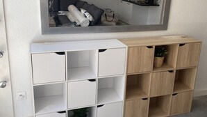 Quarto com um aparelho de ar condicionado branco, um espelho grande e um armário de madeira com vários compartimentos.