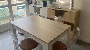Cozinha moderna com mesa de madeira, cadeiras transparentes e janela com vista para o verde.
