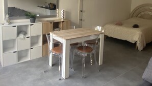 Quarto moderno e minimalista com cama, mesa de cabeceira, pequena escrivaninha com cadeira e guarda-roupa.