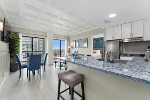 A modern kitchen with a marble countertop, stainless steel appliances, and a view of the city.
