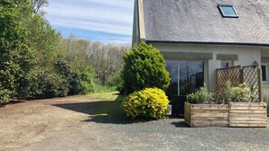 Une maison avec une allée en gravier, une clôture en bois et une petite fenêtre.