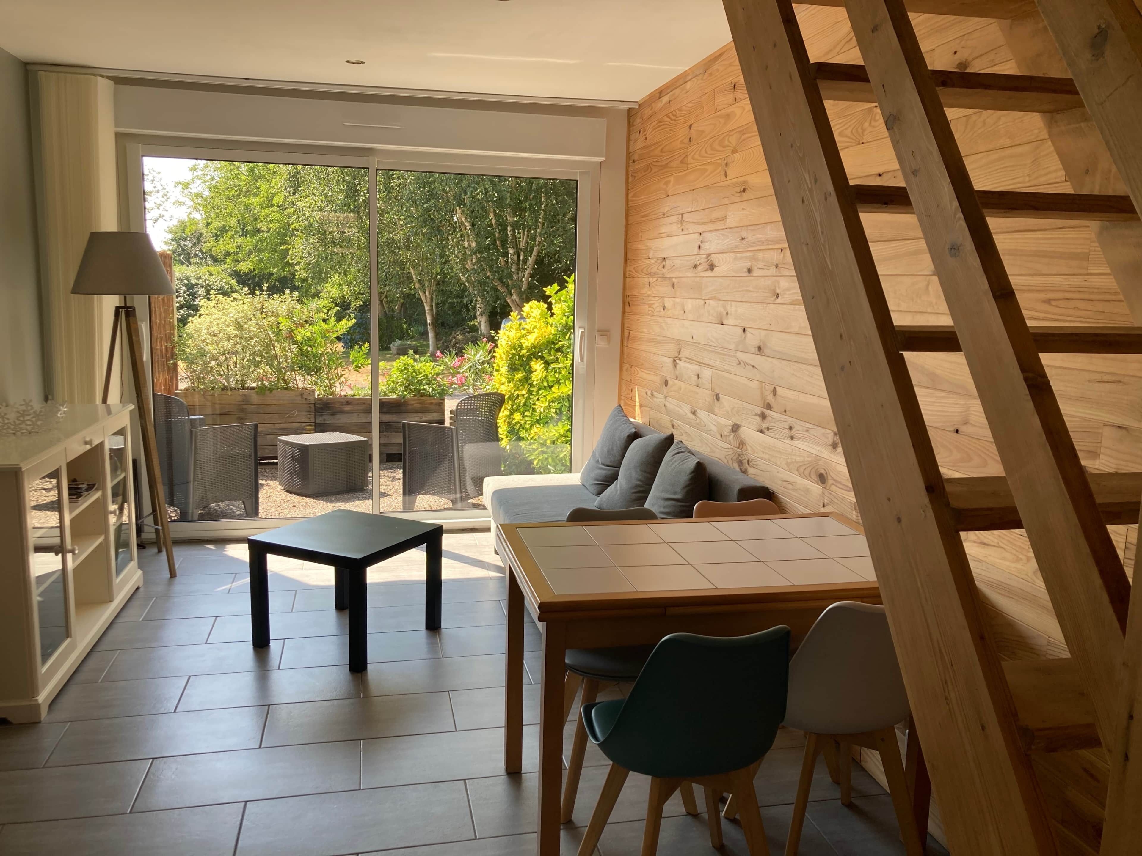 A modern interior with a wooden wall, a sofa, a table, and chairs.