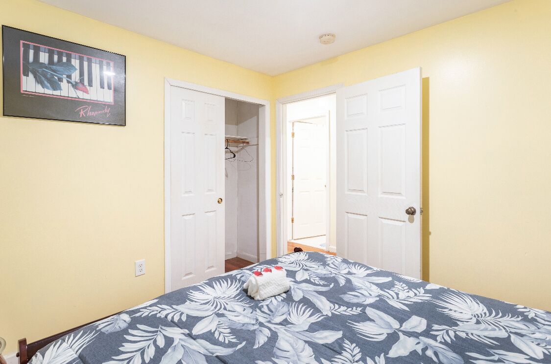 Een slaapkamer met een bed, een kledingkast en een deur naar een andere kamer.