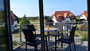 Ein Balkon mit Gartenmöbeln und einer Glastür, die auf Häuser blickt.