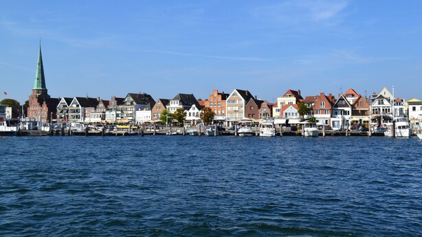 Eine Stadt am Wasser mit historischen Gebäuden und einem markanten Kirchturm.