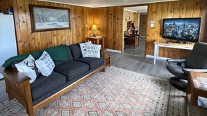 Una sala de estar acogedora con un sofá de madera, un televisor y una alfombra estampada.