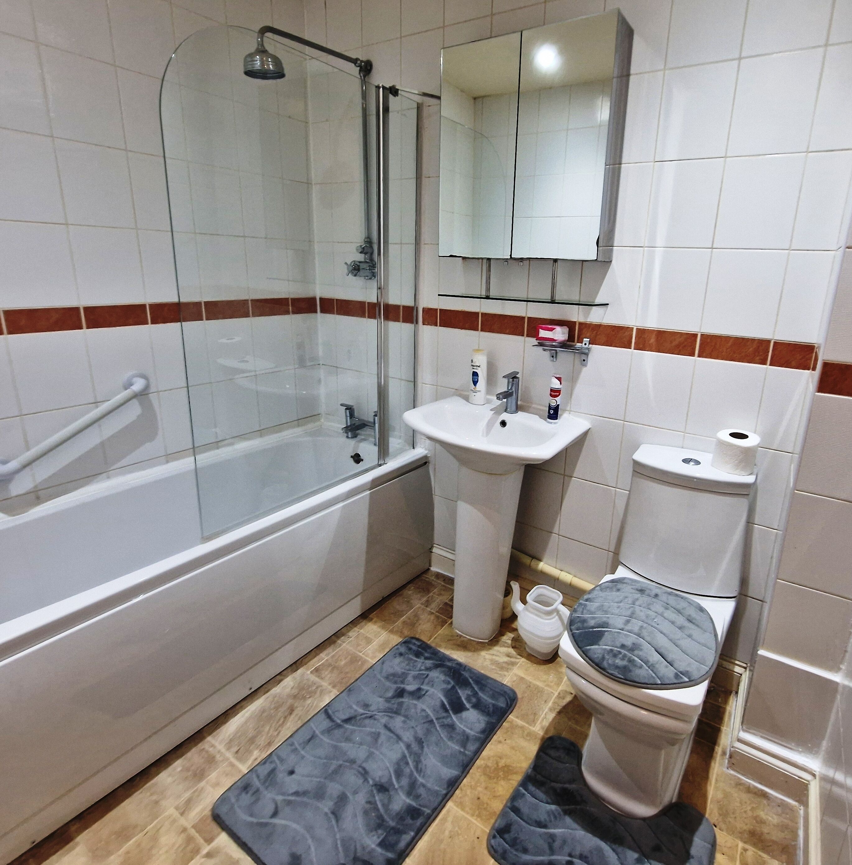 A bathroom with a glass-enclosed shower, a white sink, a toilet, and a mirror above the sink.