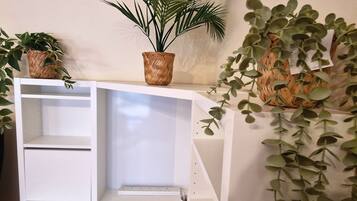 A white shelving unit with woven baskets containing green plants.
