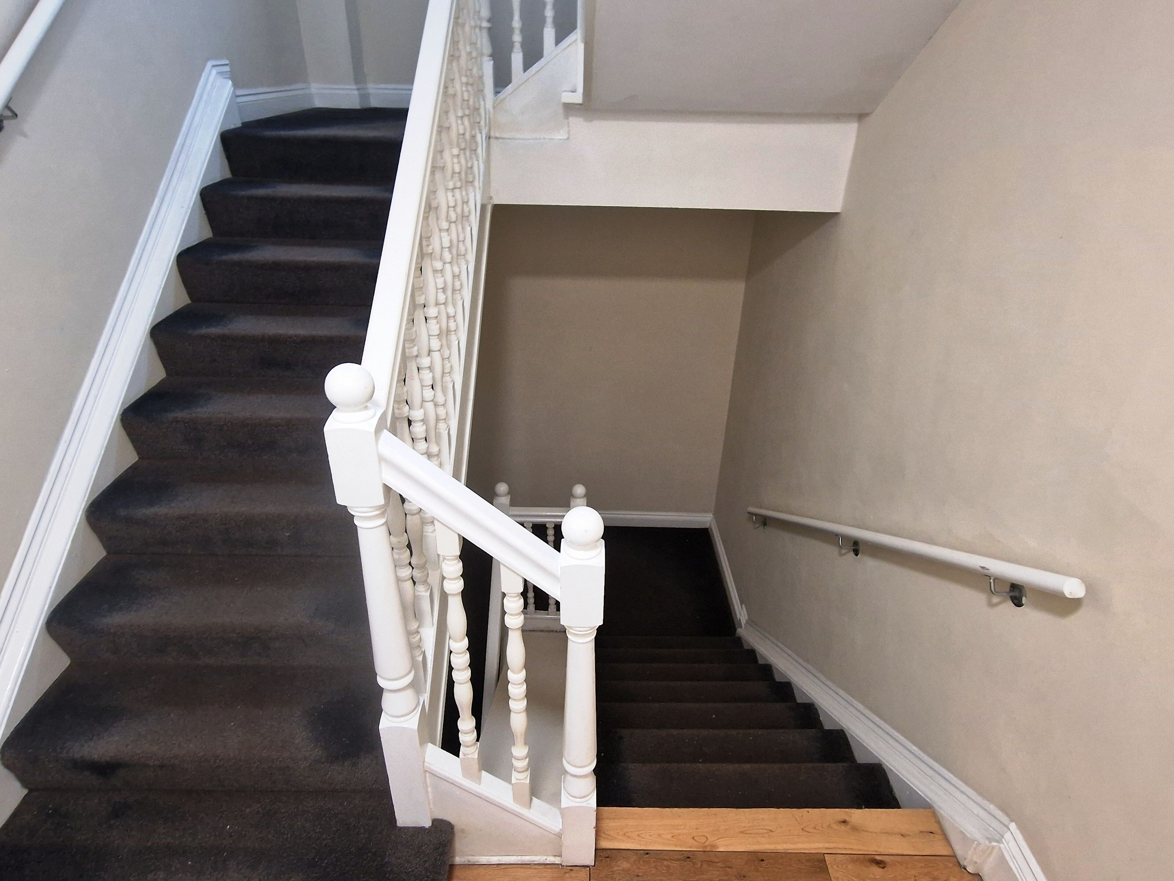 A staircase with white balusters and a handrail, leading to an upper floor.