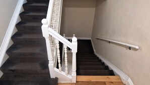 Eine Treppe mit weißen Balustraden und Geländer, die zu einer oberen Etage führt.