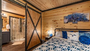 Une chambre aux murs lambrés, avec un lit, une table de chevet et un tableau accroché au mur.