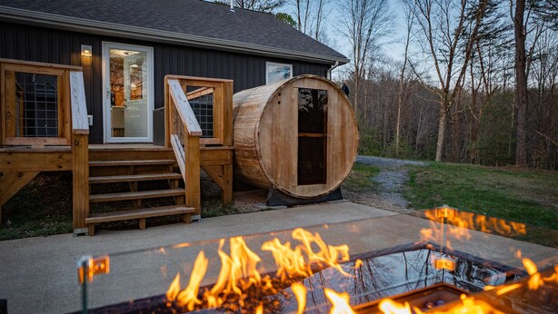 Une terrasse en bois avec un foyer et un tonneau.