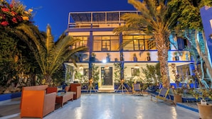 A two-story building with a balcony, outdoor seating, and potted plants. - Riad Ghazal (Essaouira)