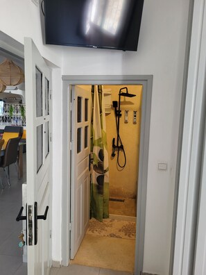 A doorway leading to a bathroom with a shower, a towel rack, and a toilet.