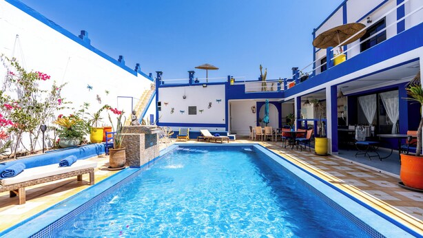 A pool area with a clear blue pool, lounge chairs, and potted plants. - Riad Ghazal (Essaouira)
