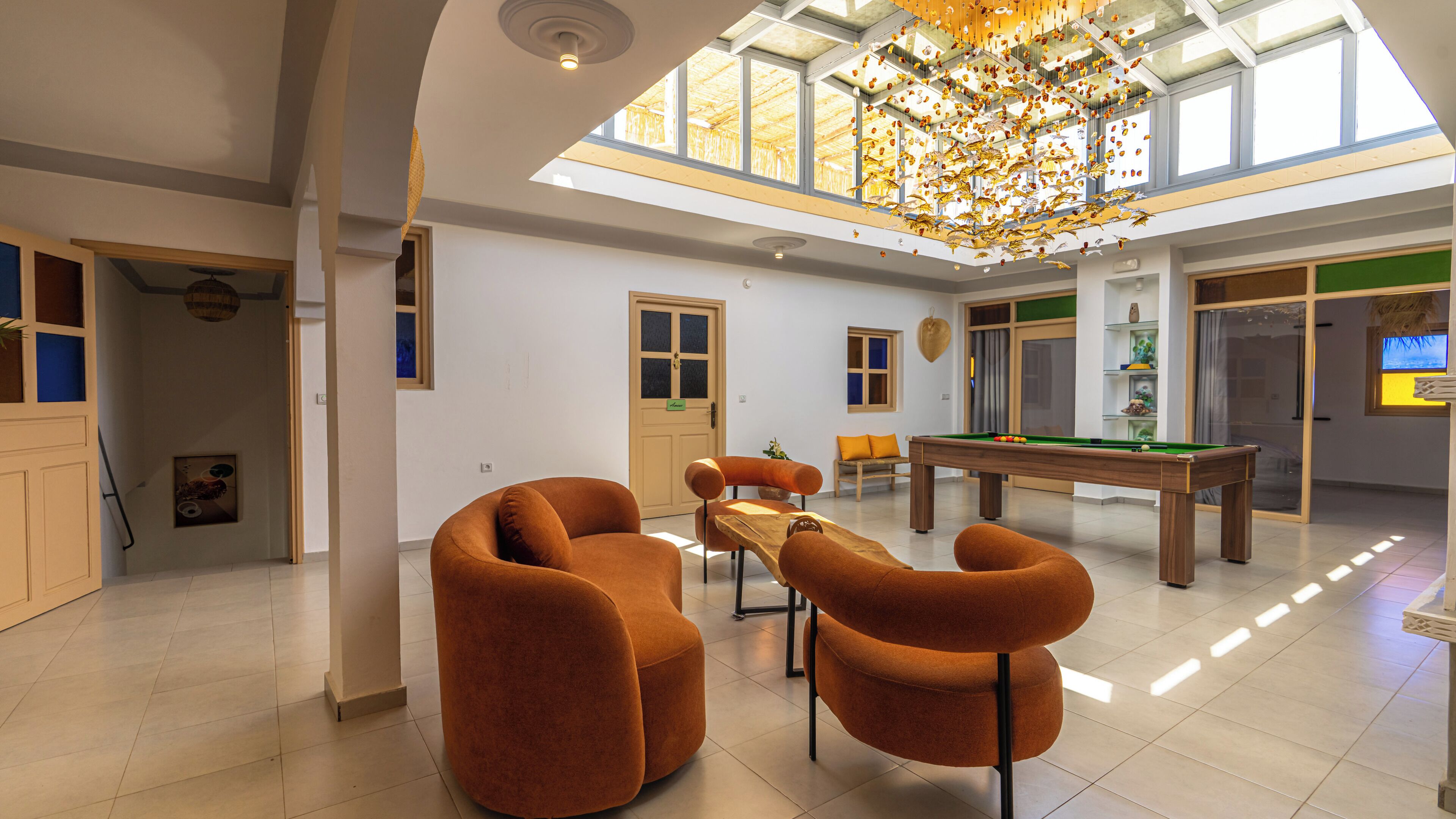 A spacious room with a pool table, comfortable seating, and a large window allowing natural light.